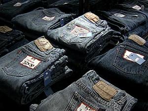 A man is arrested and charged with trademark counterfeiting after police find nearly 1,000 pairs of fake pricey jeans in his van during a traffic stop. 