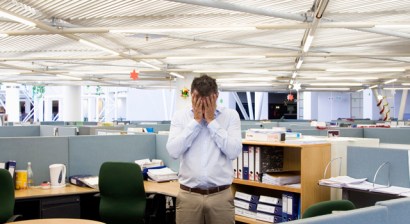 Man with hands on head in middle of office Man with hands on head in middle of office