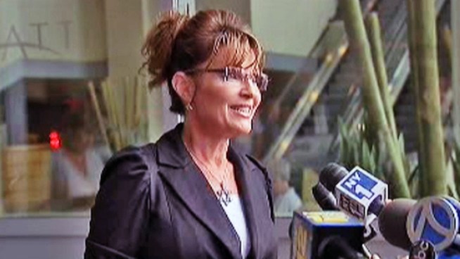 Sarah Palin pauses outside a Jersey City hotel to speak with members of the press ahead of her visit to Ellis Island and the Statue of Liberty.