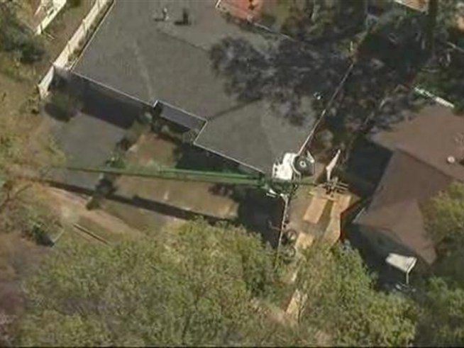 Two workers were injured after a crane tipped over and crashed against a home in <a title=