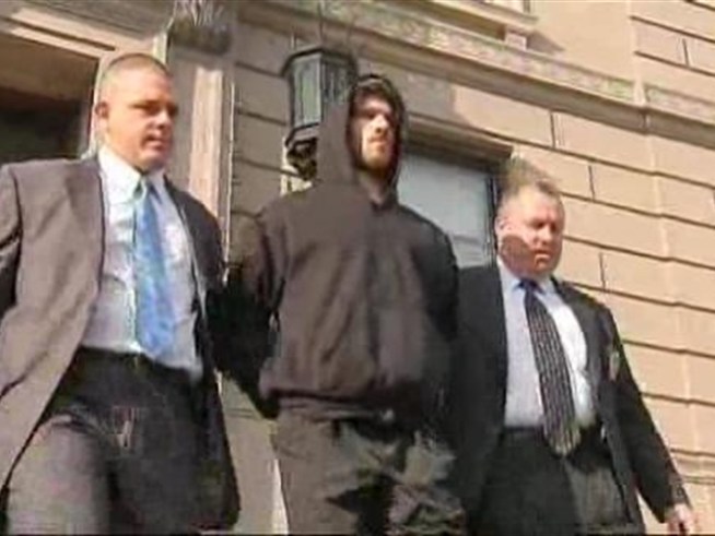 Wearing a dark hooded sweatshirt, Eric Bellucci, 30, who is accused of murdering his parents, was led out of the 120 Police Precinct station house headed for a Staten Island court.