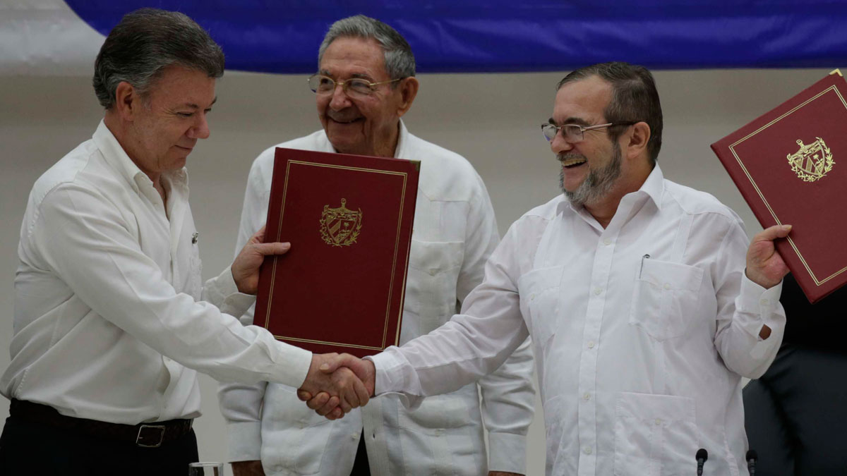 Colombian President Juan Manuel Santos, left, and Commander of the Revolutionary Armed Forces of Colombia or FARC, Timoleon Jimenez, right, shake hands during a signing ceremony of a cease-fire and rebel disarmament deal, in Havana, Cuba, on June 23, 2016