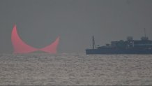 The sun, partially blocked by the moon, rises above the sea in Al Wakrah, Qatar, Dec. 26, 2019. Facebook and Twitter users were quick to draw comparisons between the reddened partial eclipse to "devil horns."