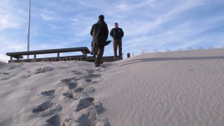 two people stand on a sand dune