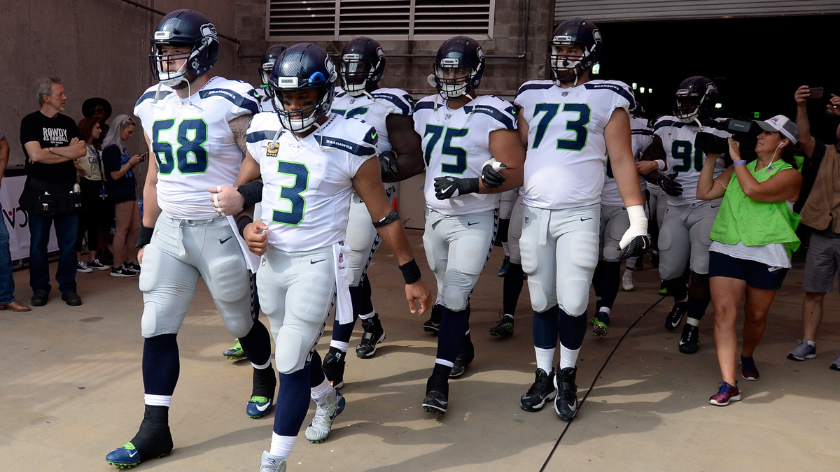 Seattle Seahawks quarterback Russell Wilson (3) and center Justin Britt (68) walk to the field with arms linked after the national anthem had been played before an NFL football game between the Seahawks and the Tennessee Titans Sunday, Sept. 24, 2017, in Nashville, Tennessee. Neither team was present on the field for the playing of the anthem.