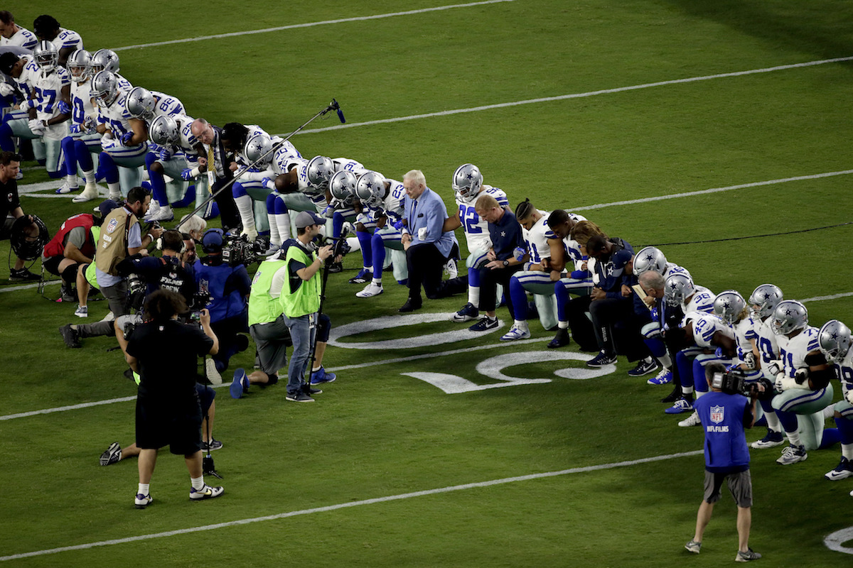 The Dallas Cowboys, led by owner Jerry Jones, center, take a knee before the national anthem prior to an NFL game against the Arizona Cardinals, Monday, Sept. 25, 2017, in Glendale, Ariz.