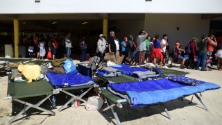 People whose homes are unsafe to enter after the previous day's magnitude 6.4 earthquake line up for lunch in an outdoor area of the Bernardino Cordero Bernard High School in Ponce, Puerto Rico, Wednesday, Jan. 8, 2020.