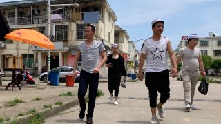 In this June 5, 2019, photo, residents of the Hui Muslim ethnic minority walk in a neighborhood near an OFILM factory in Nanchang in eastern China's Jiangxi province. The Associated Press has found that OFILM, a supplier of major multinational companies, employs Uighurs, an ethnic Turkic minority, under highly restrictive conditions, including not letting them leave the factory compound without a chaperone, worship, or wear headscarves.
