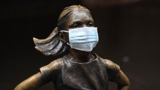 In this file photo, a surgical mask is placed on The "Fearless Girl" statue outside the New York Stock Exchange on Thursday, March 19, 2020, in New York.