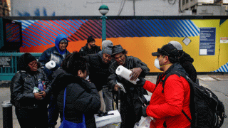 Felix Guzman and his wife Virna wear protective gloves and masks due to COVID-19 concerns as they hand out disposable gloves and sanitizing wipes to a group of people who are homeless