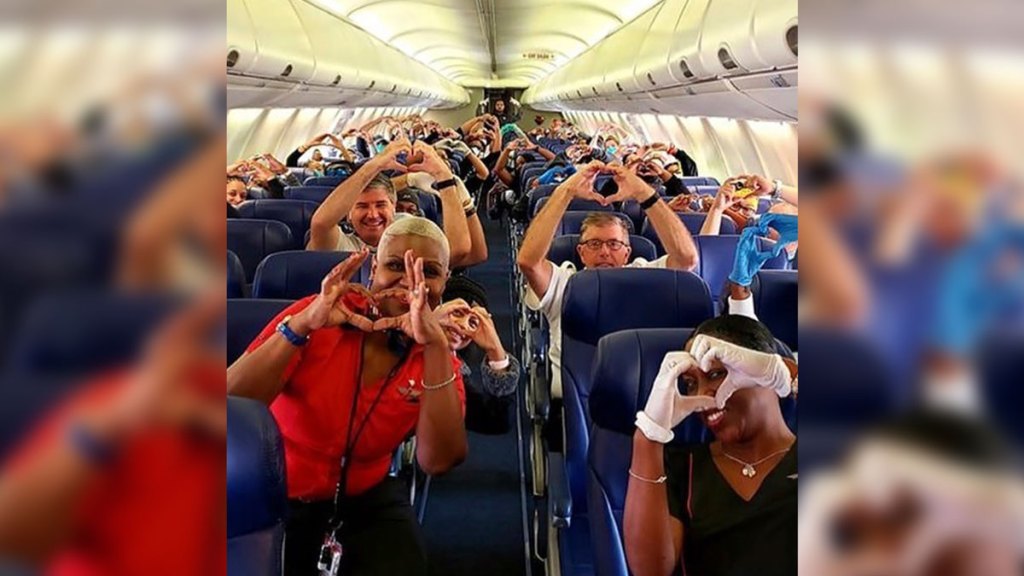 This Friday, March 27, 2020, photo provided by Southwest Airlines employee Dayartra Etheridge shows health care workers, other passengers and flight crew aboard a Southwest flight from Atlanta to New York's LaGuardia Airport holding their hands in the shape of a heart