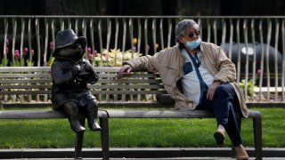 A man relaxes on a bench in London, next to a sculpture of Paddington Bear, as the country is in lockdown to help curb the spread of the coronavirus, Wednesday, April 15, 2020. The highly contagious COVID-19 coronavirus has impacted on nations around the globe, many imposing self isolation and exercising social distancing when people move from their homes.