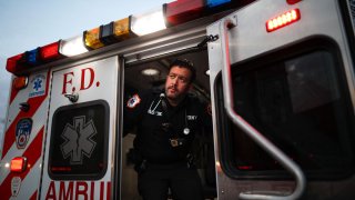 In this April 23, 2020, photo FDNY paramedic Alex Tull, who has recently recovered from COVID-19, prepares to begin his shift outside EMS station 26, the "Tinhouse", in the Bronx borough of New York.