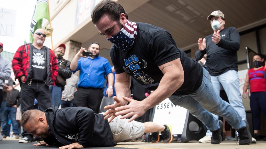Atilis Gym co-owner Ian Smith does pushups outside the storefront in Bellmawr, N.J., Monday, May 18, 2020. The gym in New Jersey reopened for business early Monday, defying a state order that shut down nonessential businesses to help stem the spread of the coronavirus.