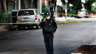 An abandoned vehicle that is believed to have been used by gunmen in an attack against the chief of police is sealed off with yellow tape and guarded by police, in Mexico City.