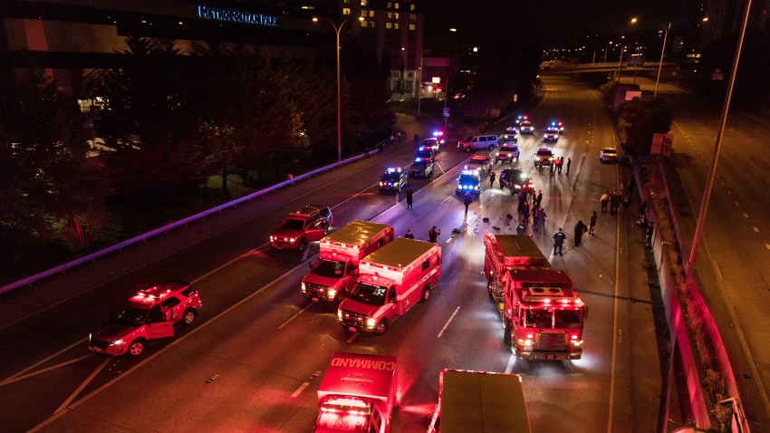 Emergency personnel work at the site where a driver sped through a protest-related closure on the Interstate 5 freeway in Seattle