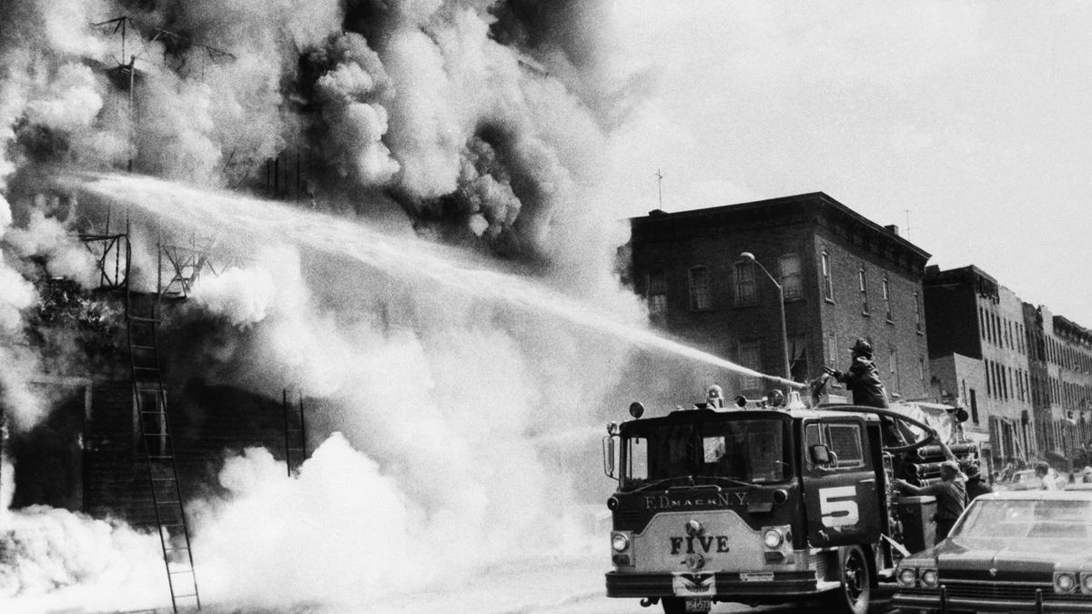Firemen fight a blaze above a row of looted stores in New York's Brooklyn borough, July 14, 1977, the day after the power failure. The stores were looted during the blackout. (AP Photo)