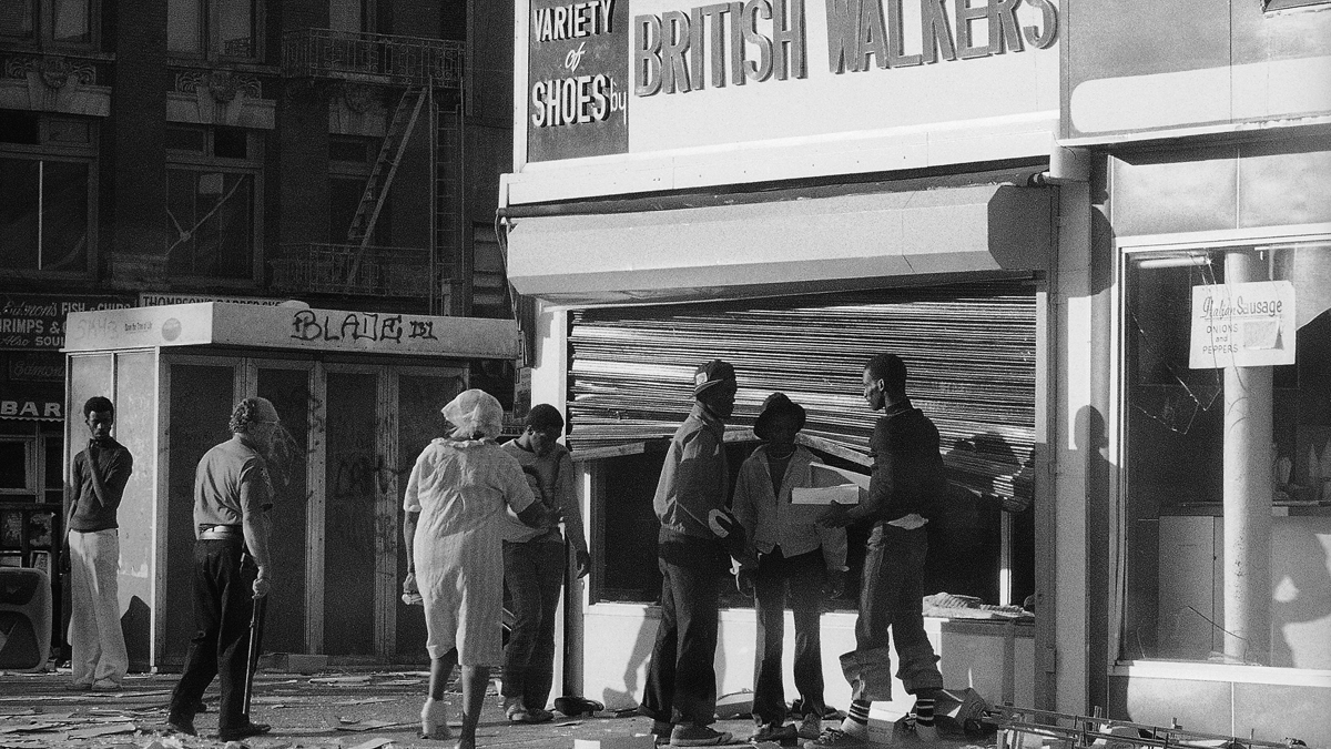 Looters in Manhattan’s Harlem section reach past a bent security gate to ransack the window of a shoe store in New York on Thursday, July 14, 1977. A massive power failure in the metropolitan New York area led to acts of vandalism in some parts of the city. (AP Photo/Ed Bailey)