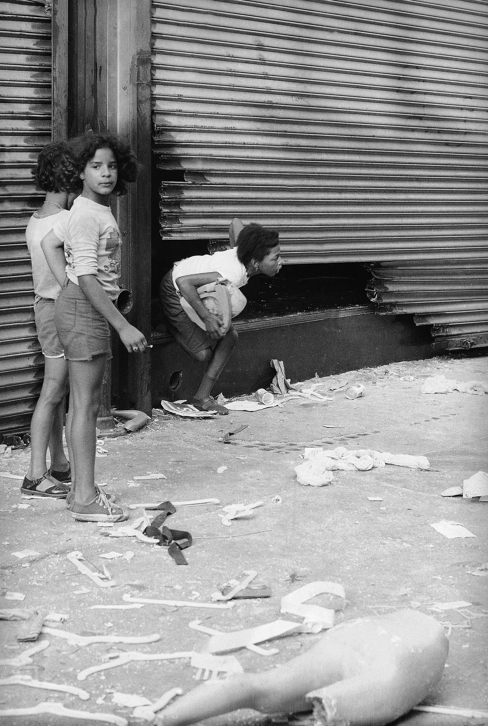 An unidentified woman, carrying a bag, comes out of the window of a looted shop in the Bedford-Stuyvesant section of the Brooklyn borough of New York City on Sunday, July 16, 1977. (AP Photo/Leonardo LeGrand)