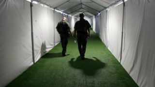 In this May 2, 2019, file photo, U.S. Border Patrol agents walk down the hallway of a new U.S. Customs and Border Protection temporary facility near the Donna International Bridge in Donna, Texas. The U.S. government says it will deport a Honduran mother and her two sick children, both of whom are currently hospitalized, to Guatemala as soon as it can get them medically cleared to travel, according to court documents and the family’s advocates.