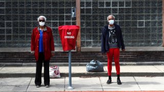 Sharon Hancock, left, and Shelia Theresa Adams pose for a portrait as they wait for the bus after visiting a friend in downtown Joliet,Ill., Monday, April 6, 2020.