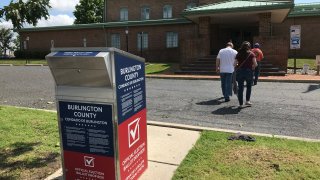 People walk away after dropping off their mail-in ballots at a drop box in Burlington County, New Jersey