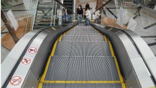 Mall shoppers riding up an escalator