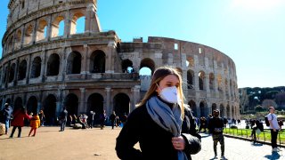 Tourist wearing a protective respiratory mask tours outside the Colosseo monument in Rome, Italy.