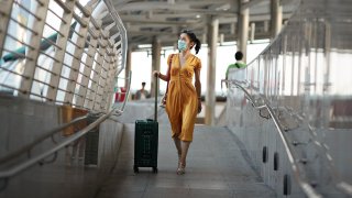 Full length of woman walking with luggage at railroad station