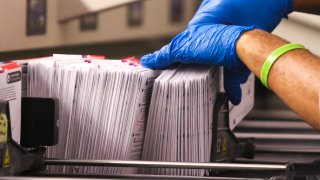 An election worker handles vote-by-mail ballots