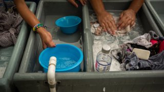 Asylum seekers wash their clothes at a makeshift migrant camp in Matamoros, Tamaulipas state, Mexico, on Friday, March 20, 2020. President Donald Trump said "non-essential" travel will be suspended across the U.S. border with Mexico as the countries combat the coronavirus outbreak.