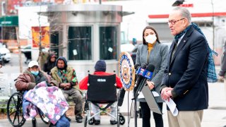 Senate Minority Leader Chuck Schumer speaks as Democratic Congresswoman from New York Alexandria Ocasio-Cortez wearing a face mask to protect herself from the coronavirus, listens during a press conference in the Corona neighbourhood of Queens on April 14, 2020 in New York City.