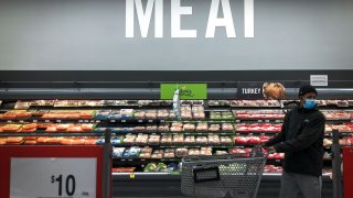 A man shops in the meat section at a grocery store