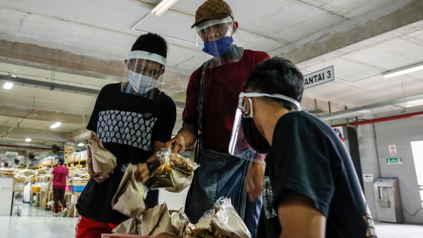 Market merchants wearing face mask and shield as they buy foods amid coronavirus disease (COVID-19) pandemic in Denpasar's traditional market, Bali, Indonesia on May 15 2020.