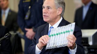 Texas Governor Greg Abbott displays COVID-19 test collection vials as he addresses the media during a press conference held at Arlington Emergency Management on March 18, 2020 in Arlington, Texas.