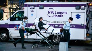 NEW YORK, NY – APRIL 13: EMS workers wheel a patient out of NYU Langone Health hospital during the coronavirus pandemic on April 13, 2020 in New York City. COVID-19 has spread to most countries around the world, claiming over 119,000 lives with infections at over 1.9 million people. (Photo by Noam Galai/Getty Images)