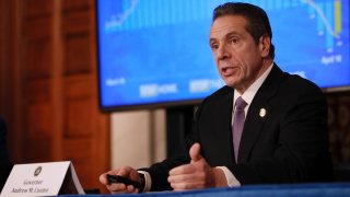 Gov. Andrew Cuomo sitting behind a desk during his daily coronavirus press briefing.