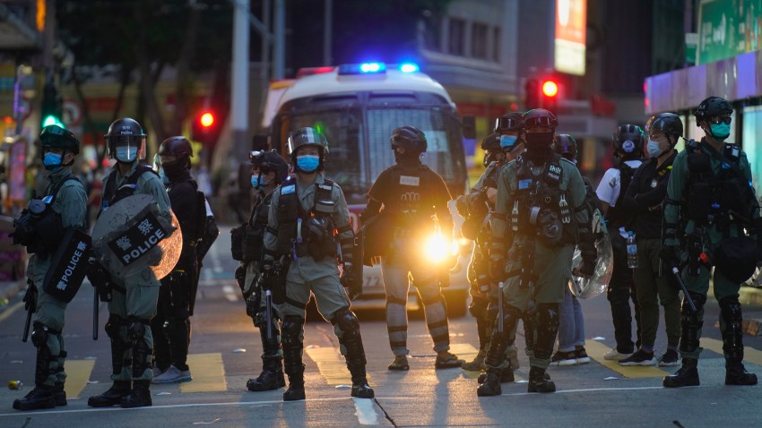 Police stand guard on a street after clearing a road block during a march marking the anniversary of the Hong Kong handover from Britain to China, Wednesday, July. 1, 2020, in Hong Kong.