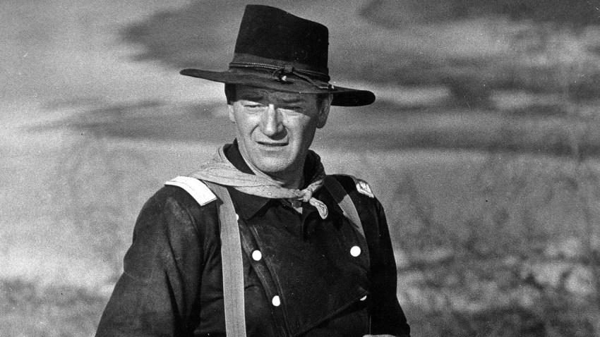In this undated photo, John Wayne appears during the filming of "The Horse Soldiers." In the latest move to change place names in light of U.S. racial history, leaders of Orange County’s Democratic Party are pushing to drop film legend Wayne’s name, statue and other likenesses from the county’s airport because of his racist and bigoted comments.