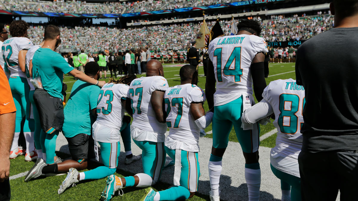 Miami Dolphins offensive tackle Laremy Tunsil (67), Maurice Smith (27), Jarvis Landry (14) lock hands with teammates during the playing of the national anthem before an NFL football game against the New York Jets Sunday, Sept. 24, 2017, in East Rutherford, N.J.