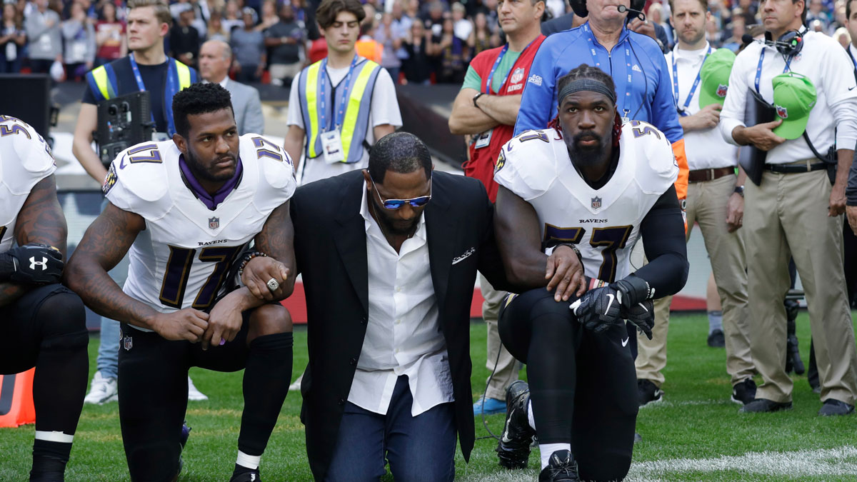Baltimore Ravens wide receiver Mike Wallace, from left, former player Ray Lewis and inside linebacker C.J. Mosley lock arms and kneel down during the playing of the national anthem before an NFL football game against the Jacksonville Jaguars at Wembley Stadium in London, Sunday, Sept. 24, 2017.