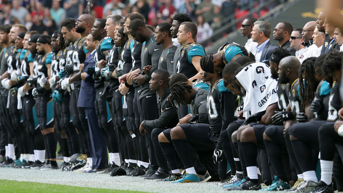 Jacksonville Jaguars players lock arms and kneel down during the playing of the national anthem before an NFL football game against the Baltimore Ravens at Wembley Stadium in London, Sunday, Sept. 24, 2017.