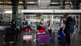 In this June 21, 2020, file photo, passengers wearing face masks arrive at Adolfo Suarez-Barajas international airport, outskirts Madrid, Spain, Sunday, June 21, 2020.
