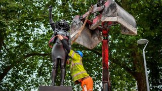 A contractor uses ropes to secure the statue "A Surge of Power (Jen Reid) 2020" by artist Marc Quinn, which had been installed on the site of the fallen statue of the slave trader Edward Colston, as they prepare to remove and load it into a recycling and skip hire lorry, in Bristol, Thursday, July 16, 2020. The sculpture of protestor Jen Reid was installed without the knowledge or consent of Bristol City Council and was removed by the council 24 hours later.