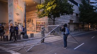 Protestors remove a fence and move it to another area to block a road near the Multnomah County Justice Center in Portland, Oregon