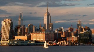 A boat sails in the Hudson River under the Empire State Building and Chrysler Building