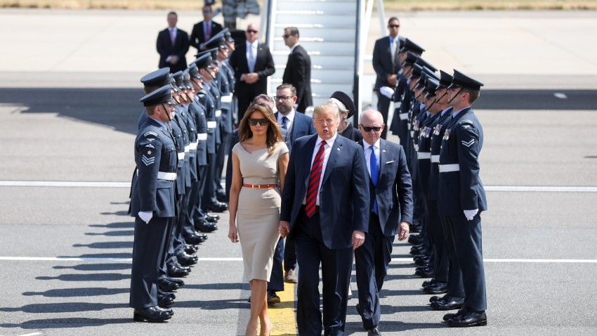 U.S. President Donald Trump, center, U.S. First Lady Melania Trump, left, and Woody Johnson, U.S. ambassador to the United Kingdom, make their way to Marine One after arriving nat London Stansted Airport in Stansted, U.K., on Thursday, July 12, 2018. Trump will avoid London as much as possible as he's whisked off on a tour of prime British real estate to keep him away from protesters during his U.K. visit.