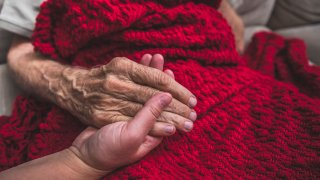 Caretaker holding elderly patient's hand