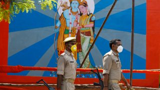 Policemen walk past an image of Hindu god Ram on the eve of a groundbreaking ceremony of a temple dedicated to Ram in Ayodhya, India, Tuesday, Aug. 4, 2020.