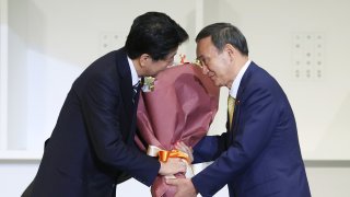 to outgoing Prime Minister Shinzo Abe (L) after the ruling LDP party's leadership election in Tokyo on September 14, 2020. - Japan's ruling party on September 14 elected chief cabinet secretary Yoshihide Suga as its new leader, making him all but certain to replace Shinzo Abe as the country's next prime minister.